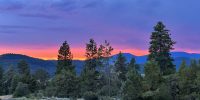 Pink and purple twilight sky over the Cascade foothills with the Beattys Butte road sign and ponderosa pines along a community road at Ridgewater Properties in Klamath Falls, Oregon